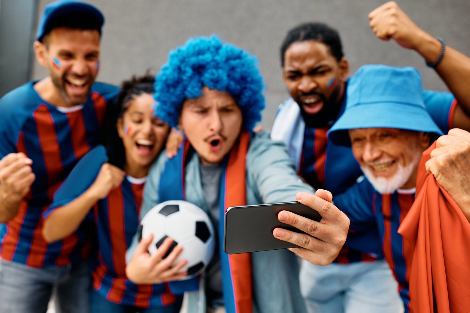 Close up of sports fans watching a football match via live stream on mobile phone.